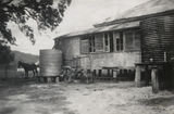Picture relating to Cooktown - titled 'Water tanks for drinking and washing at the rear of a Cooktown house, 1942'