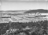 Picture relating to Ainslie - titled 'Braddon, Reid and Civic Centre from Mt Ainslie. Ainslie Hotel, Limestone Avenue in foreground. Black Mountain in background.'